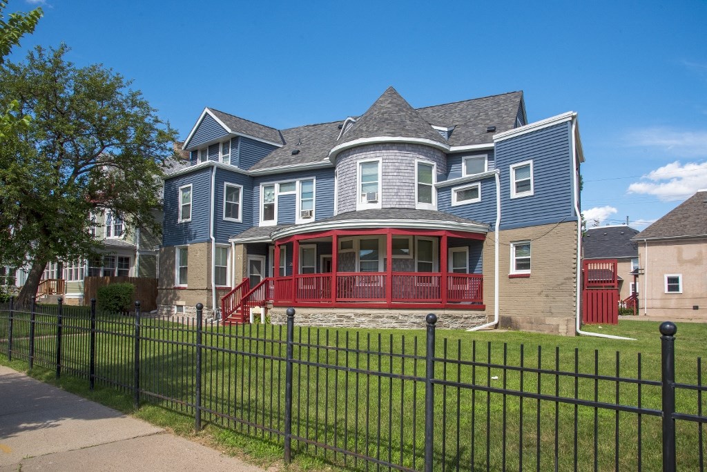 a blue house with a red porch and a black fence