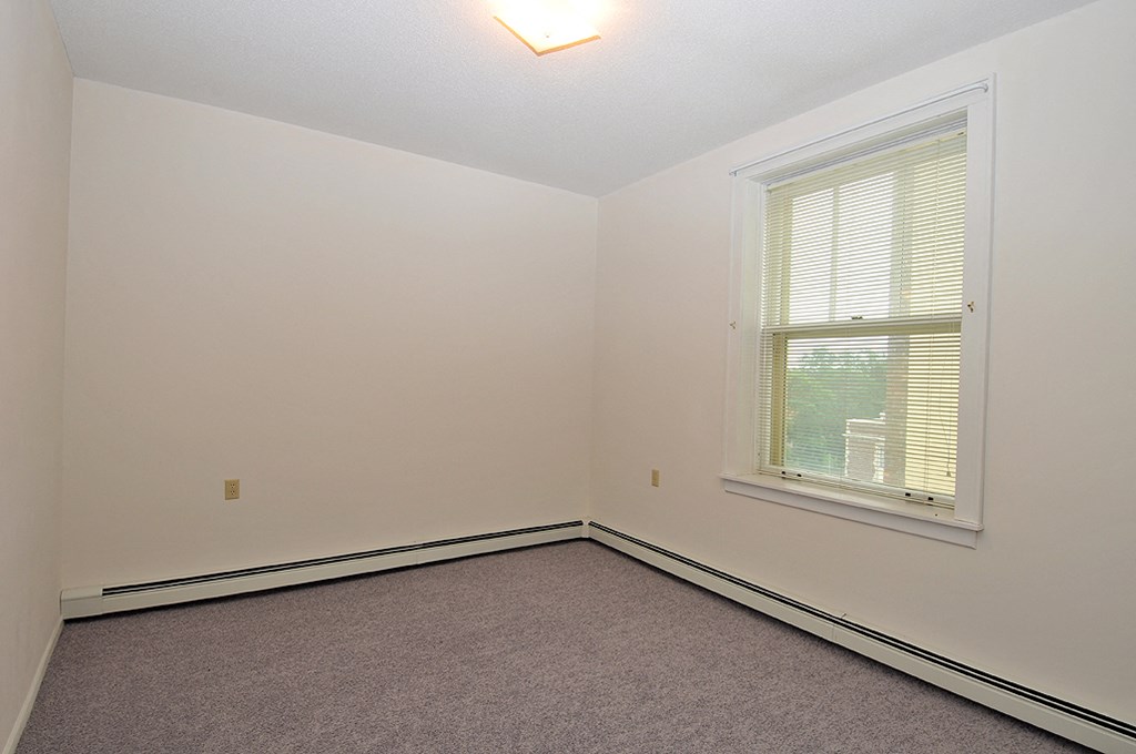 a bedroom with white walls and a window