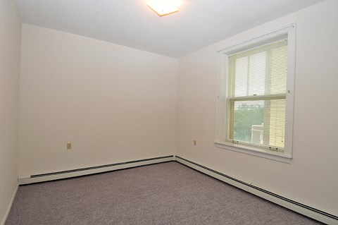 a bedroom with white walls and a window