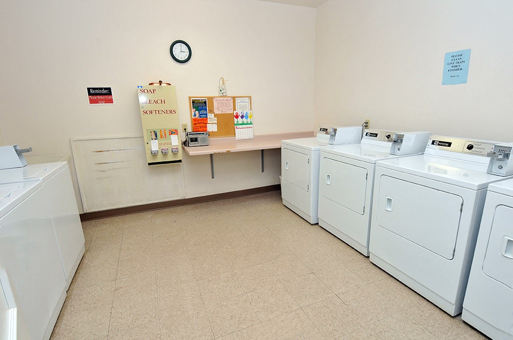 a washer and dryer room with laundry machines and a counter with a clock