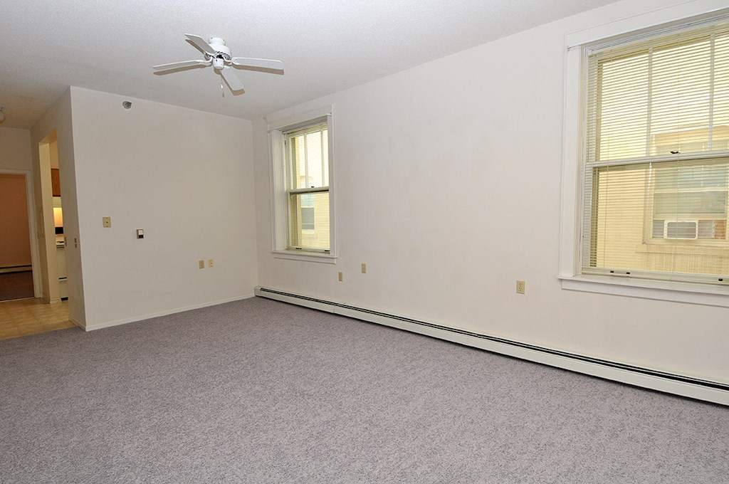 an empty bedroom with a ceiling fan and two windows