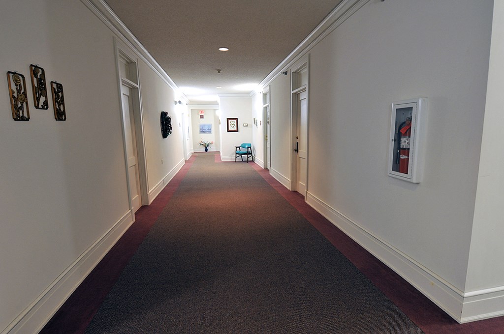 a long hallway with a red carpet and white walls and doors