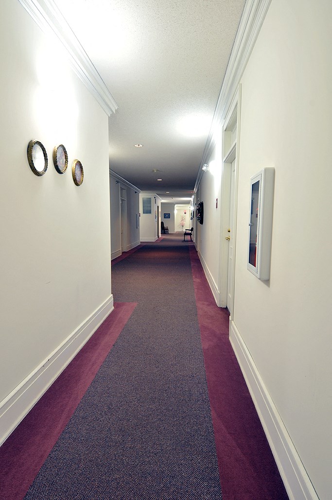 a hallway with a carpeted floor and white walls with a red rug