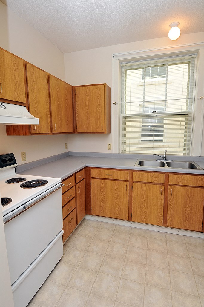 an empty kitchen with white appliances and wooden cabinets
