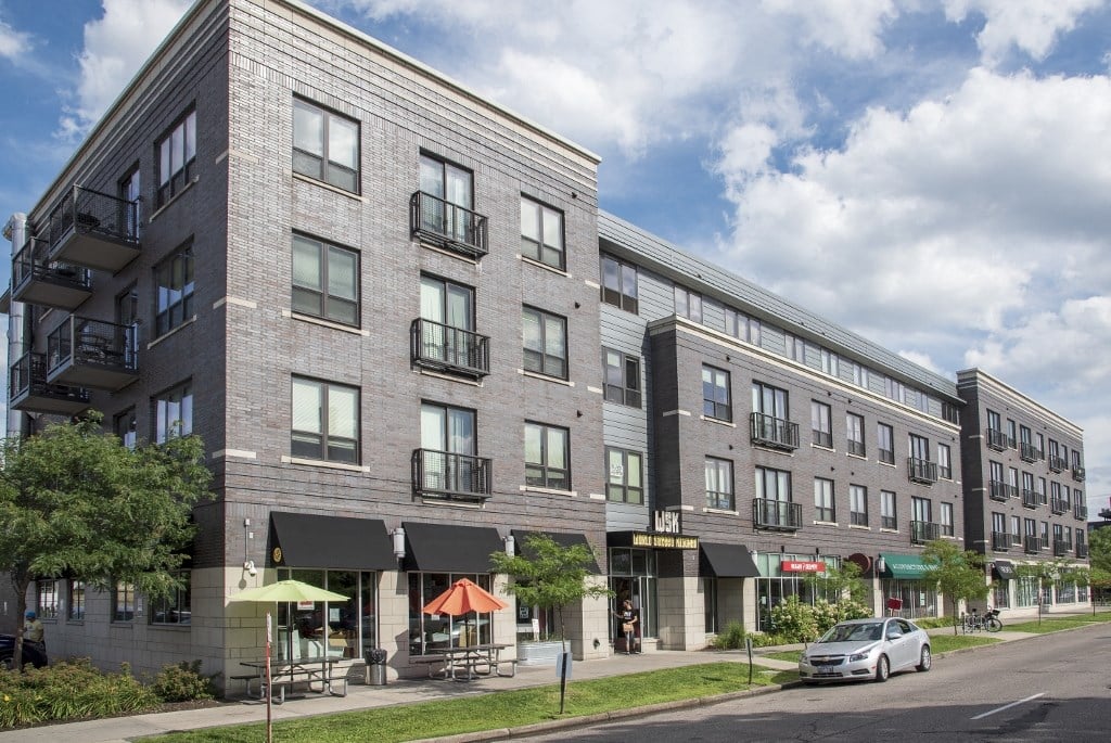 a large apartment building on a city street with a car