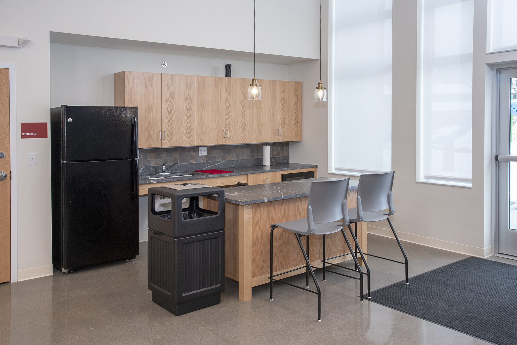 a kitchen with a refrigerator and a counter with chairs