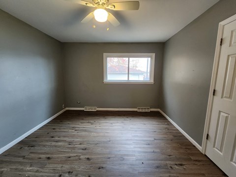 an empty bedroom with a window and a ceiling fan