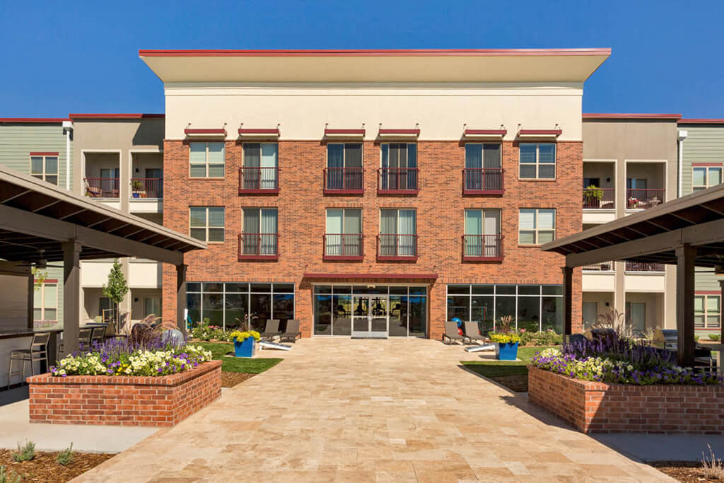 Westlake Greens outdoor kitchen area with pathway leading to brick fitness center building