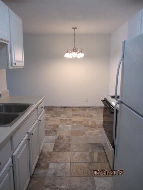 a kitchen with white cabinets and a refrigerator and a sink