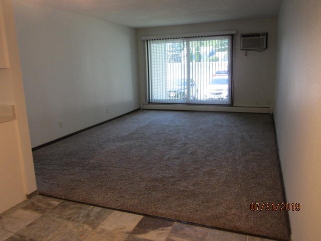 an empty living room with a window and carpet