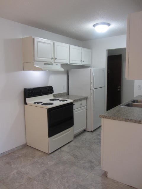a white kitchen with a stove and a refrigerator