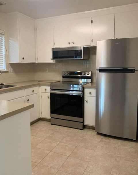 A kitchen with white cabinets and a stainless steel refrigerator.