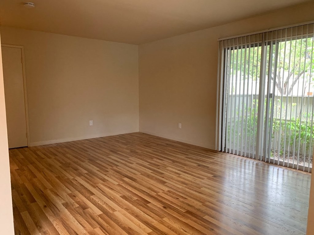 an empty living room with wood floors and a sliding glass door