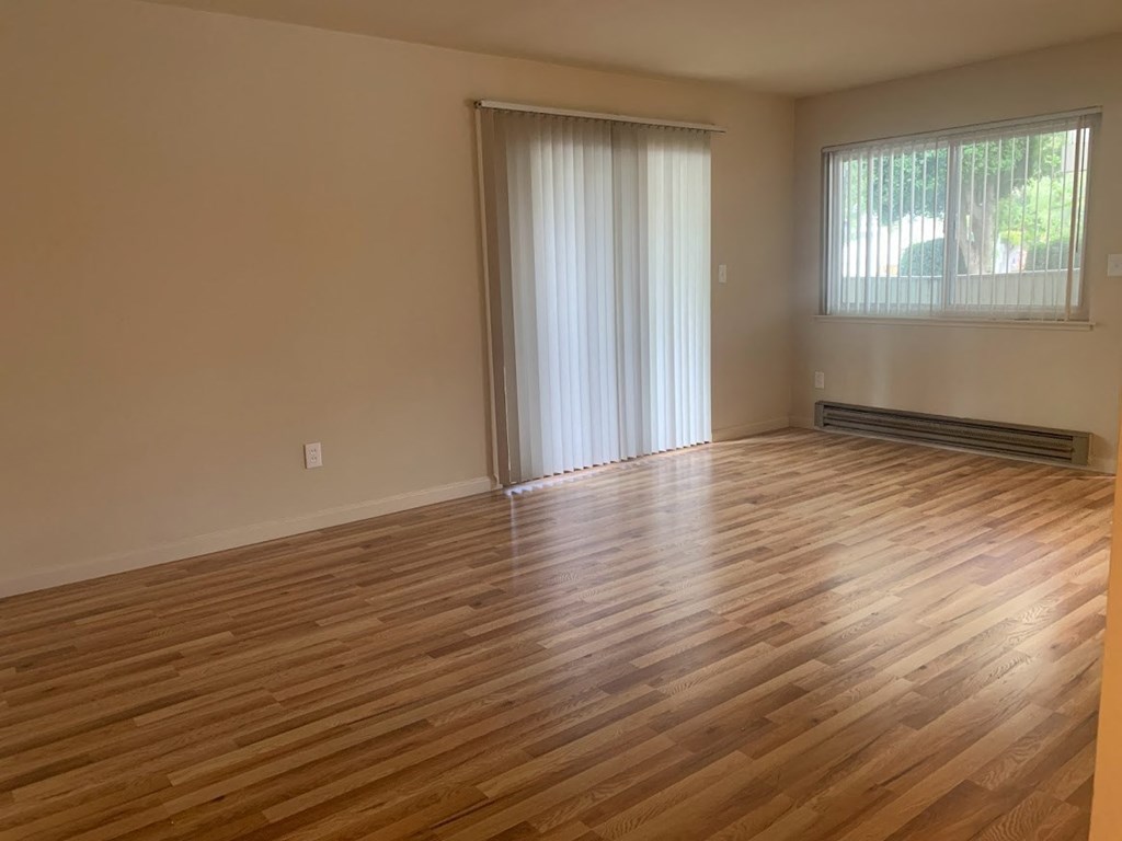an empty living room with wooden floors and a sliding glass door