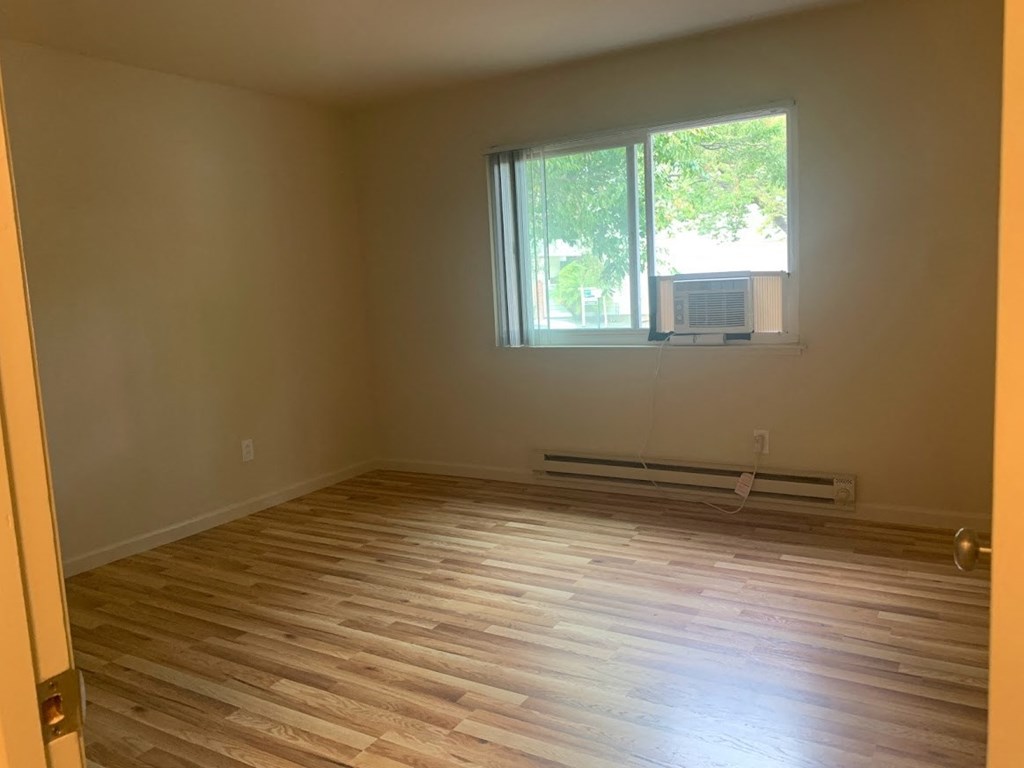 an empty room with wooden floors and a window