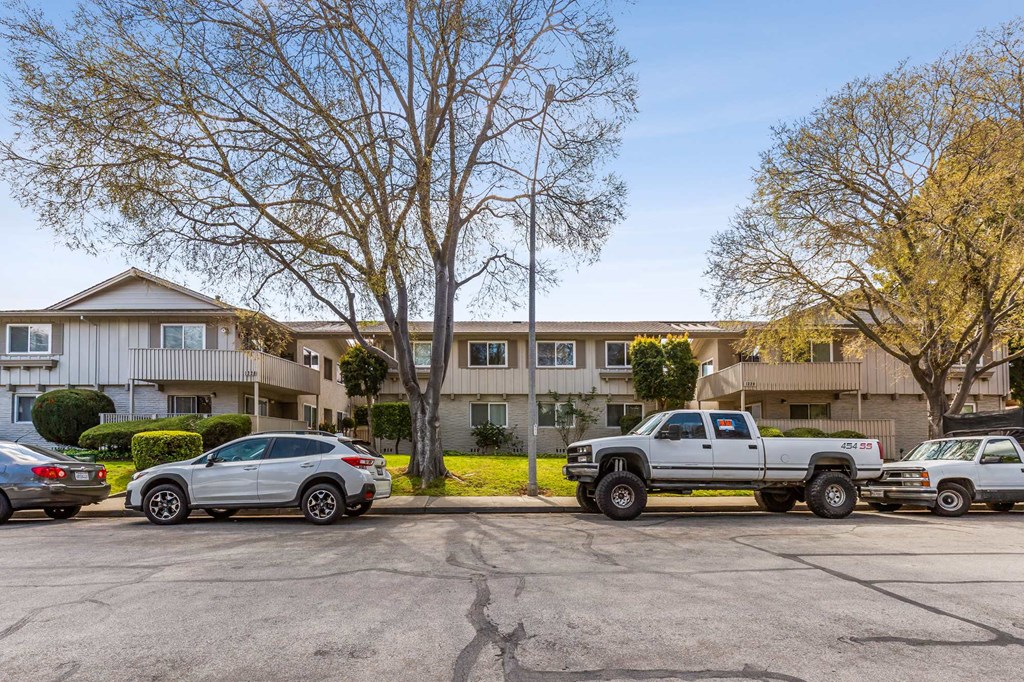 a parking lot with cars in front of an apartment building