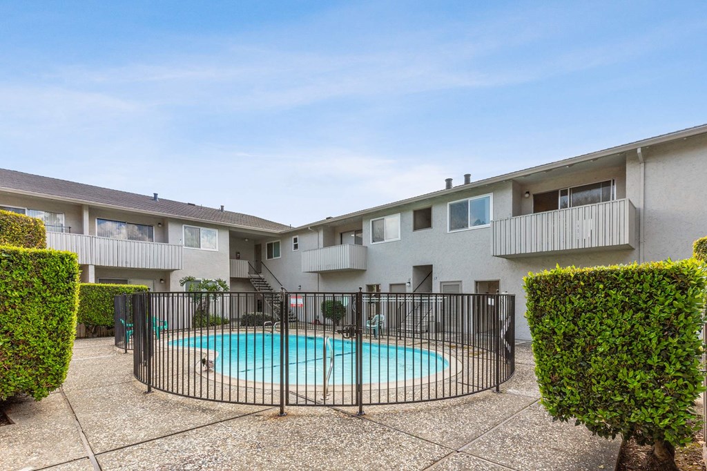 a swimming pool with a wrought iron fence in front of an apartment building