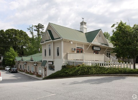 a white house with a white fence and a green roof