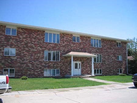 a red brick apartment building with a car parked in front