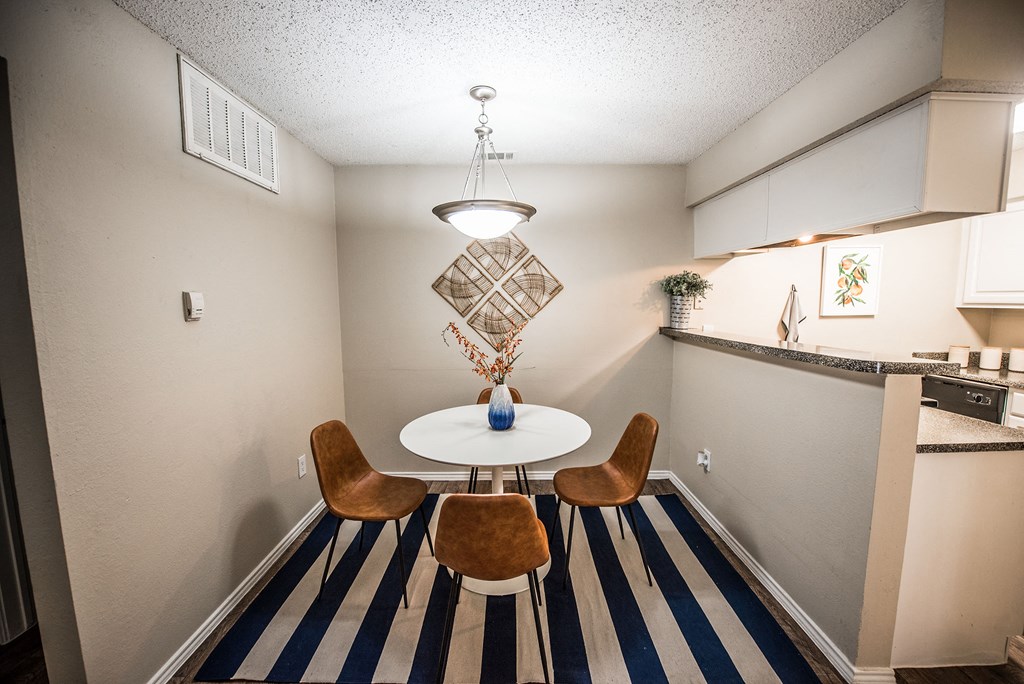 a dining room with a table and chairs and a kitchen with a counter and a