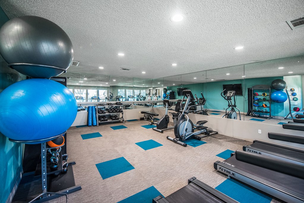 a gym with treadmills and weights and a ball on the floor