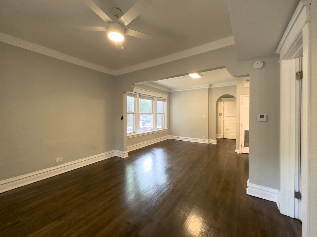 an empty living room with wood floors and a ceiling fan