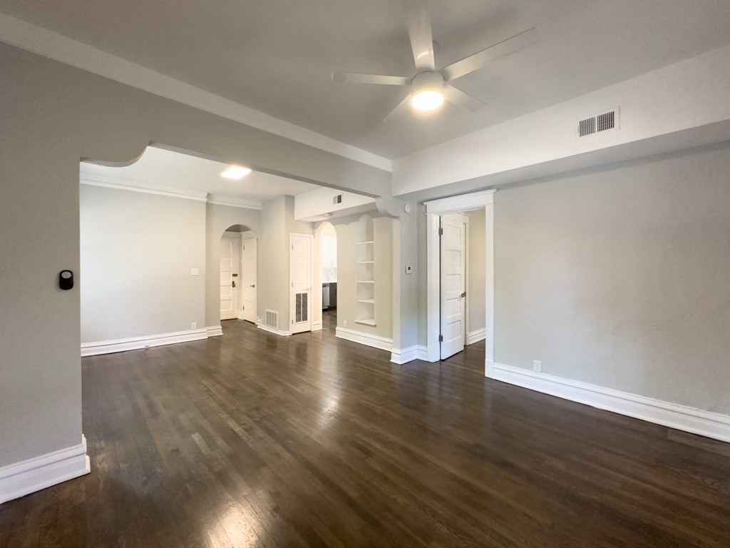 an empty living room with a ceiling fan and wood flooring