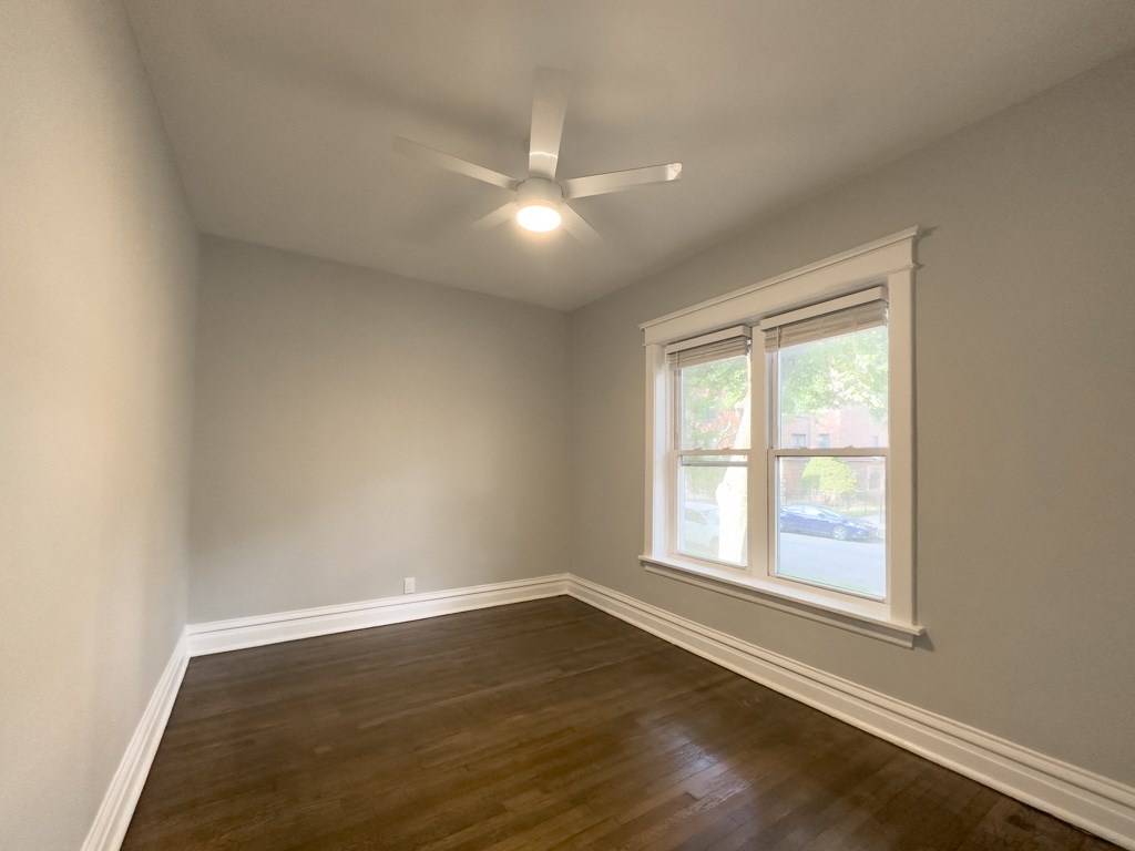 an empty living room with a window and a ceiling fan