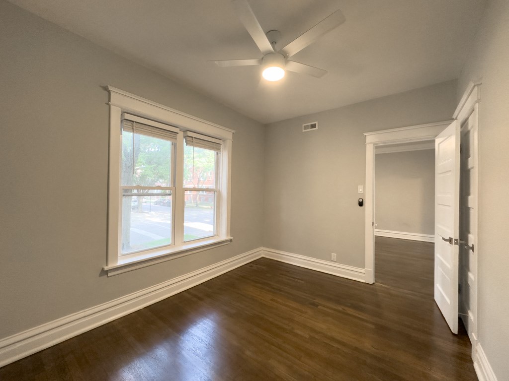 an empty living room with wooden floors and a ceiling fan