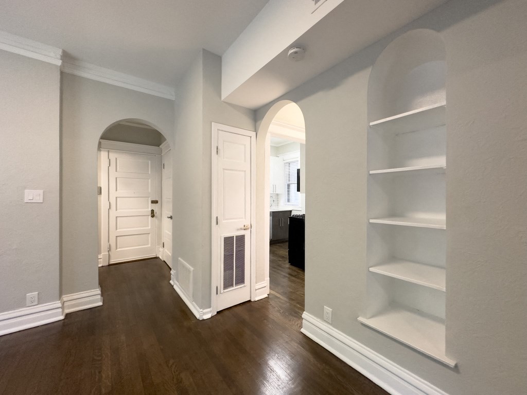a renovated living room and hallway with white shelves and wood floors