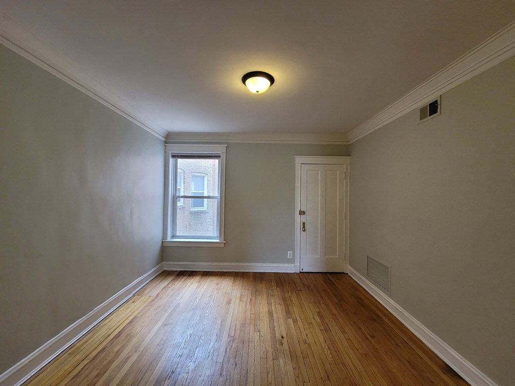 an empty living room with wood floors and a window