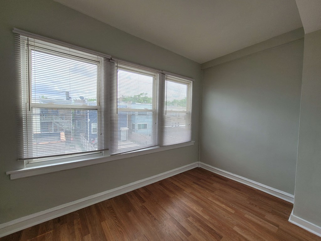 an empty living room with three windows and wood floors