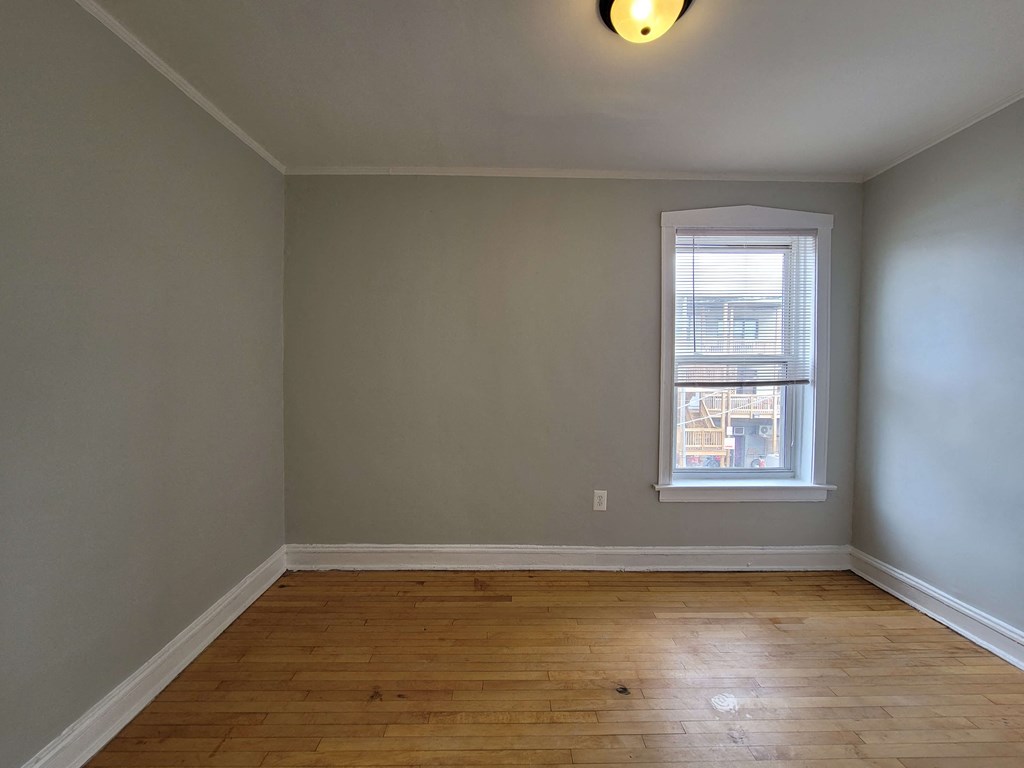 an empty room with a window and wooden floors