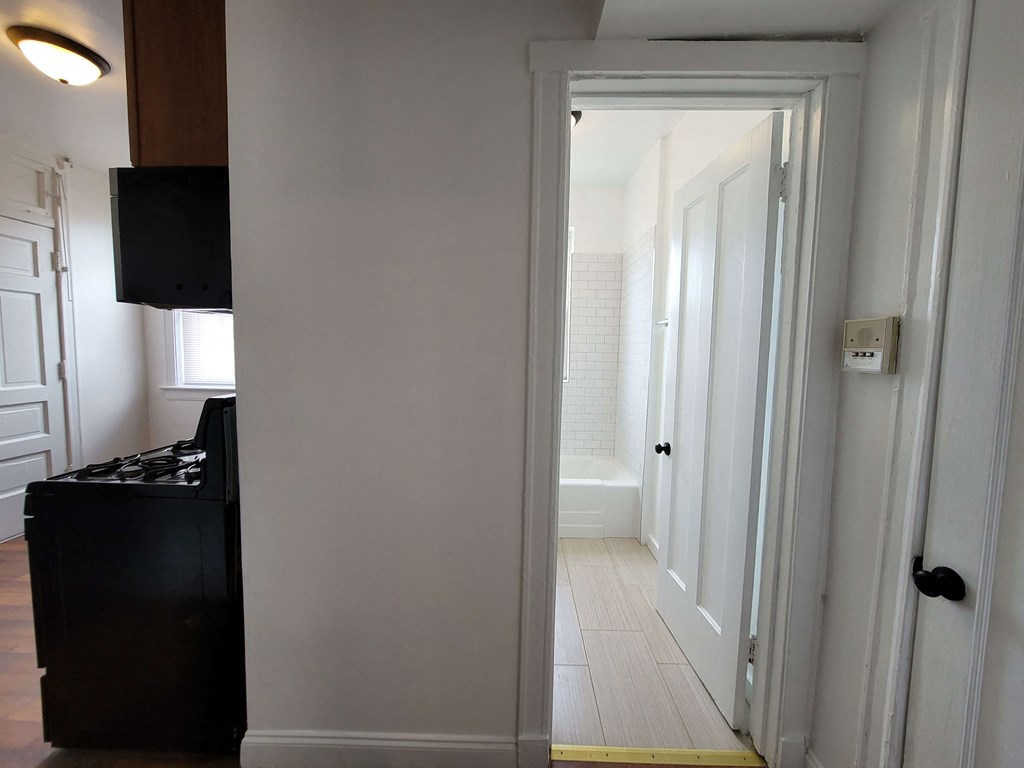 a small kitchen and hallway with a door to a bathroom