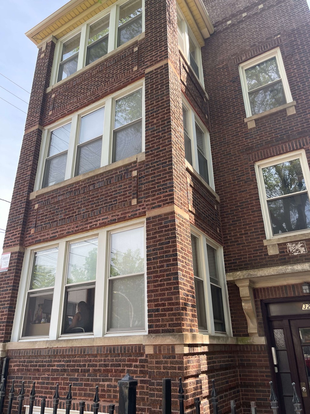 a red brick building with white windows and a black fence