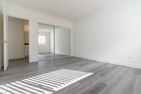 an empty living room with white walls and a mirrored closet