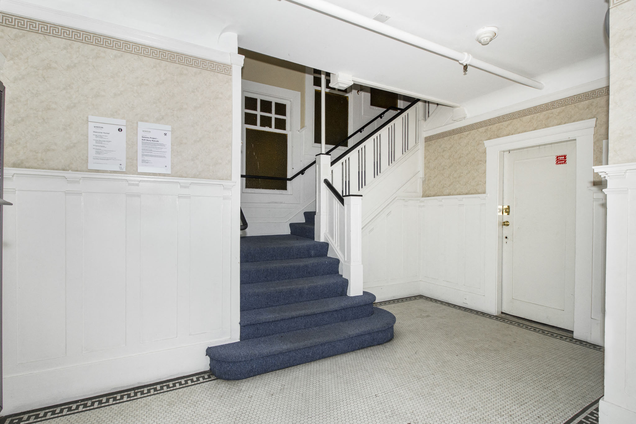 A hallway with a staircase and a door.