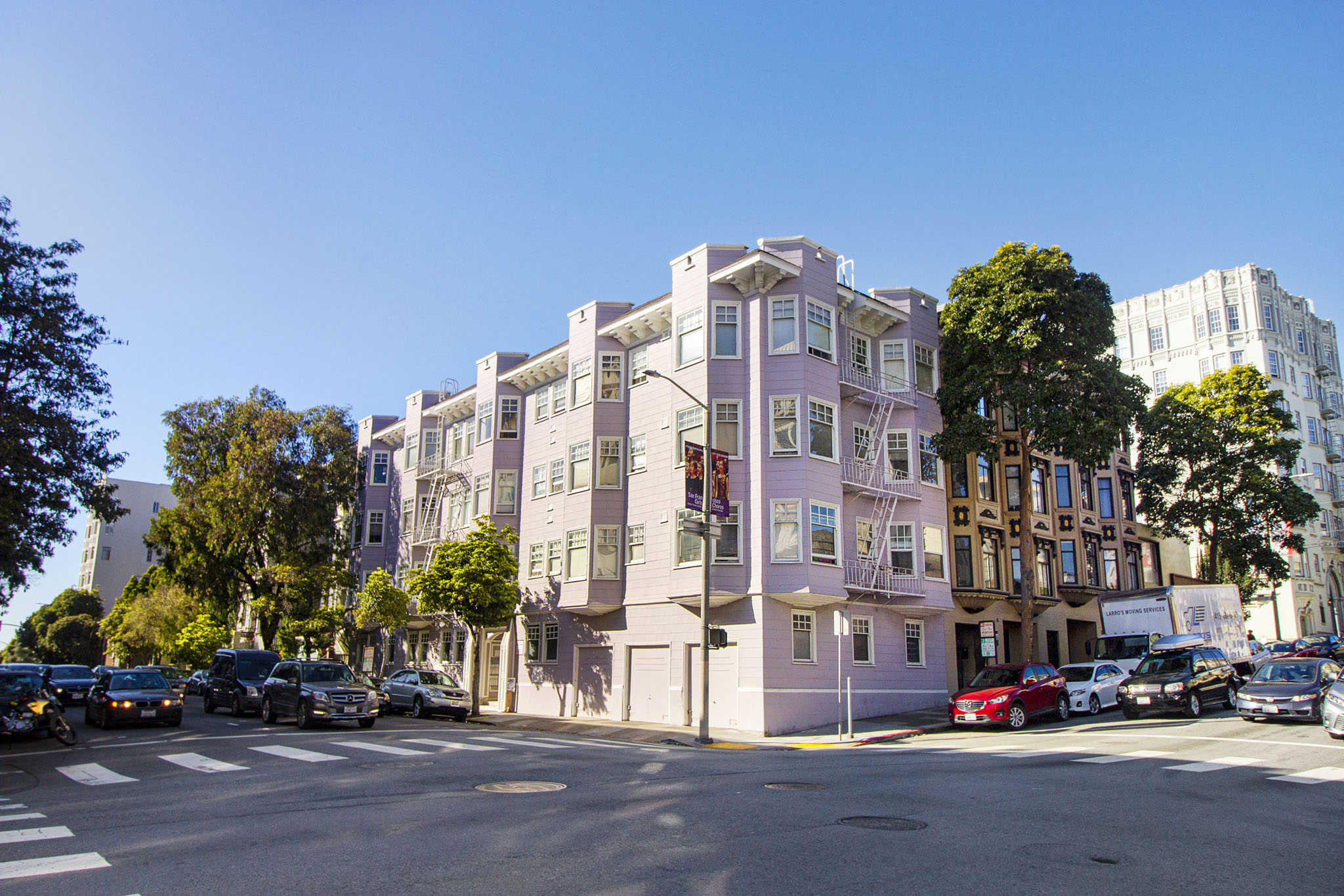 A street view of a row of buildings with cars parked on the side.