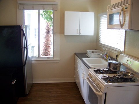 A kitchen with a black fridge and white cabinets.