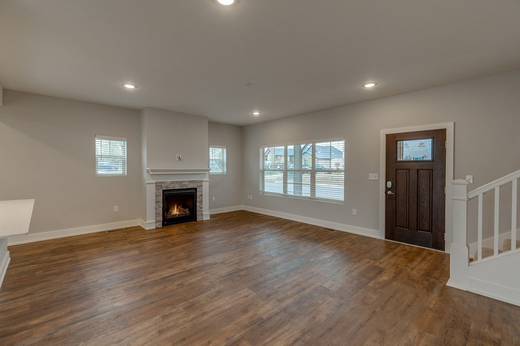 an empty living room with a fireplace and wooden floors
