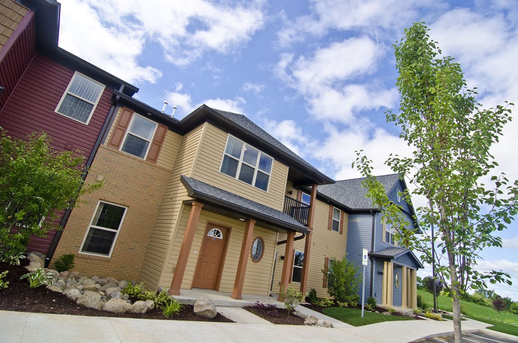a yellow house with a blue house and a tree in front of it