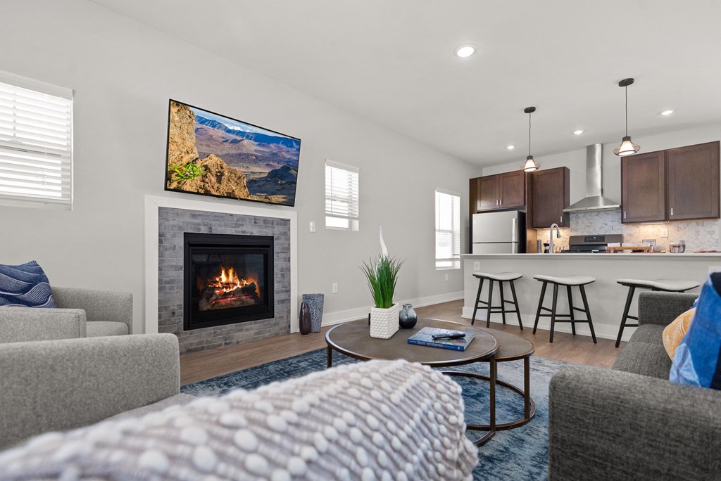 a living room with a fireplace and a kitchen with a bar