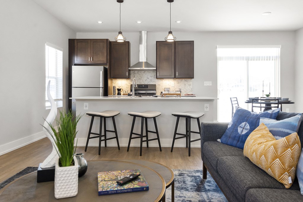 a living room with a kitchen with a bar and stools