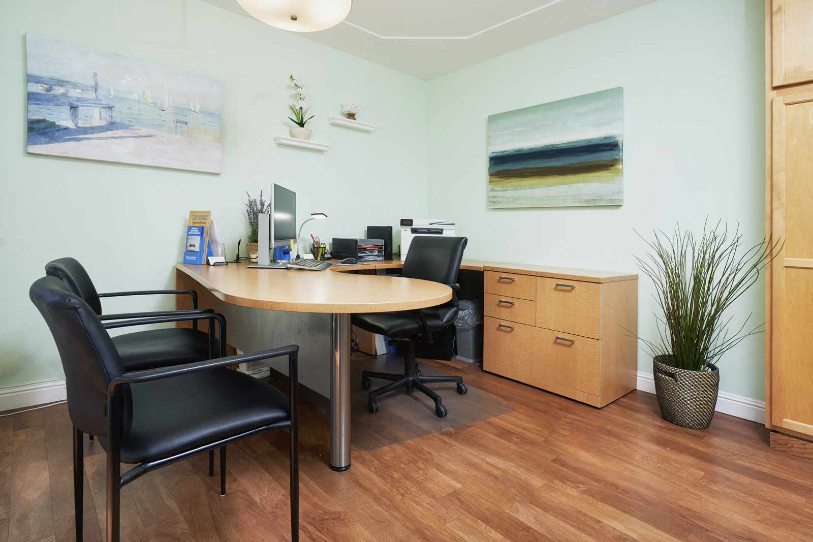 A conference room with a table, chairs, and two paintings on the wall.