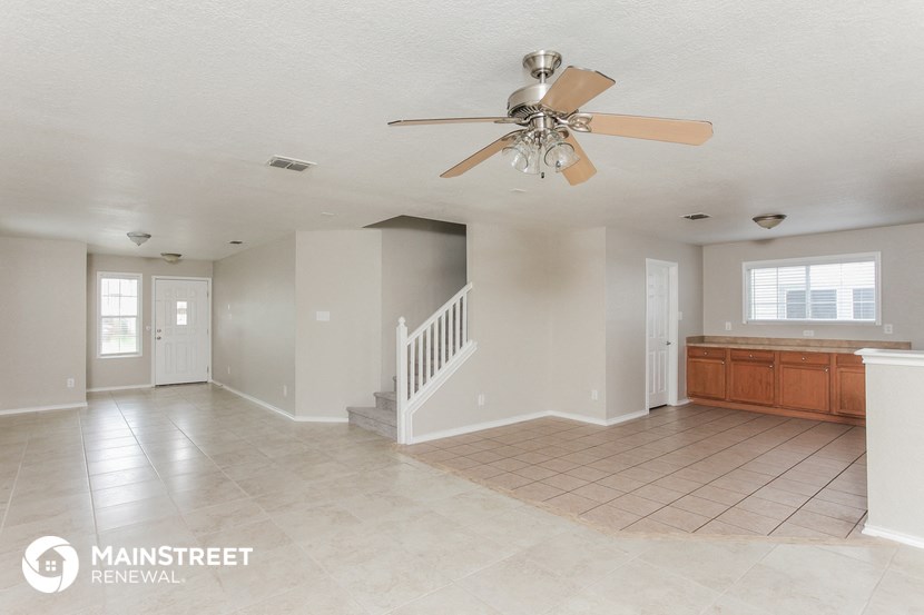 an empty living room with a ceiling fan