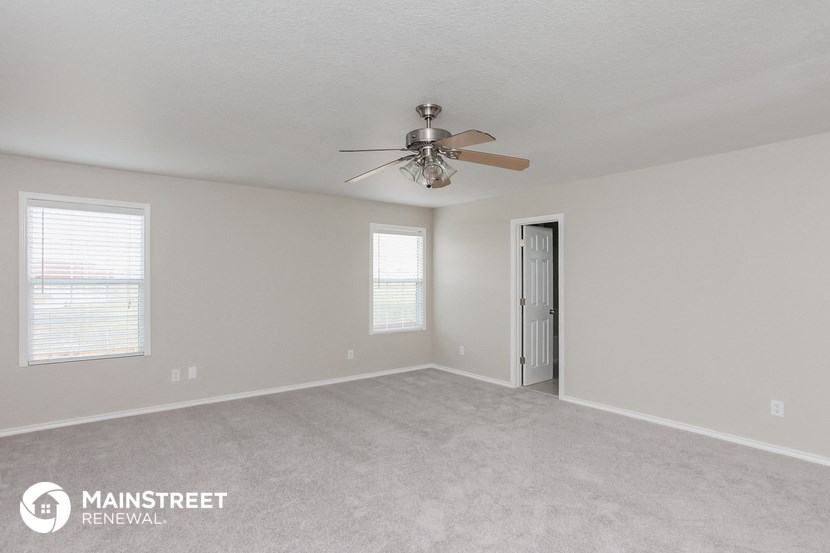 the spacious living room with ceiling fan and carpeting