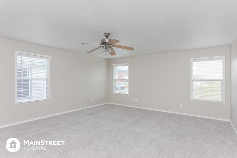 a bedroom with white walls and a ceiling fan