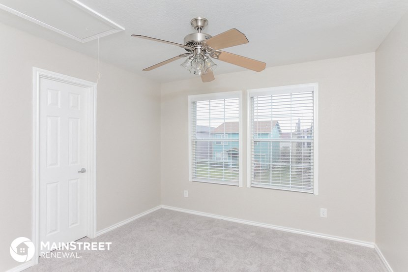 a bedroom with a ceiling fan and two windows