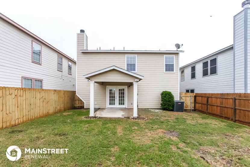a backyard with a white house and a wooden fence