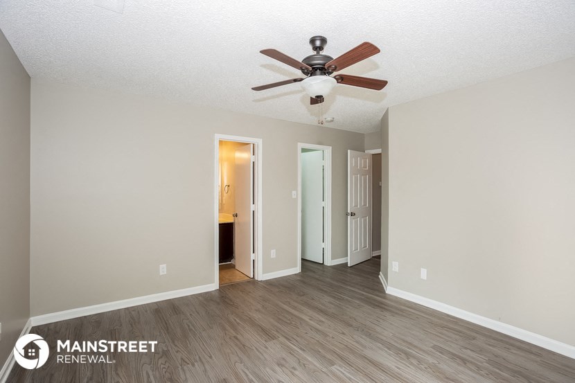 the spacious living room with ceiling fan and wood flooring